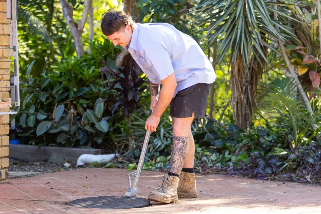 Plumber performing drain cleaning on residential pathway in Sandstone Point